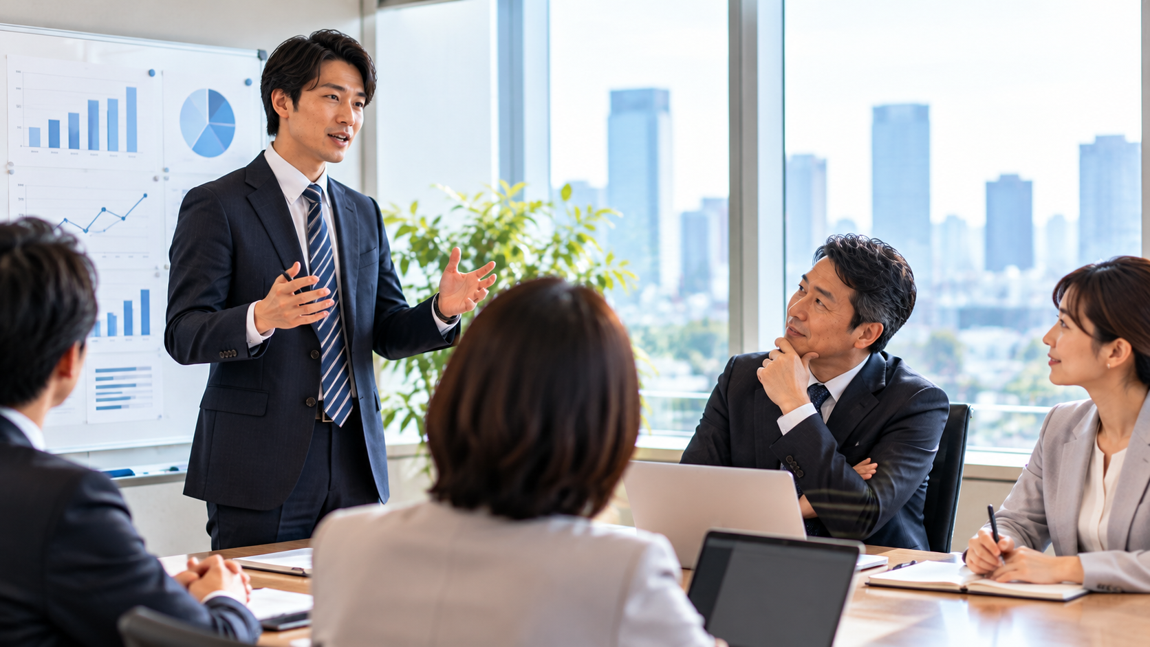 会議室で営業担当者が成功事例を説明し、マネージャーとメンバーが聞いている様子